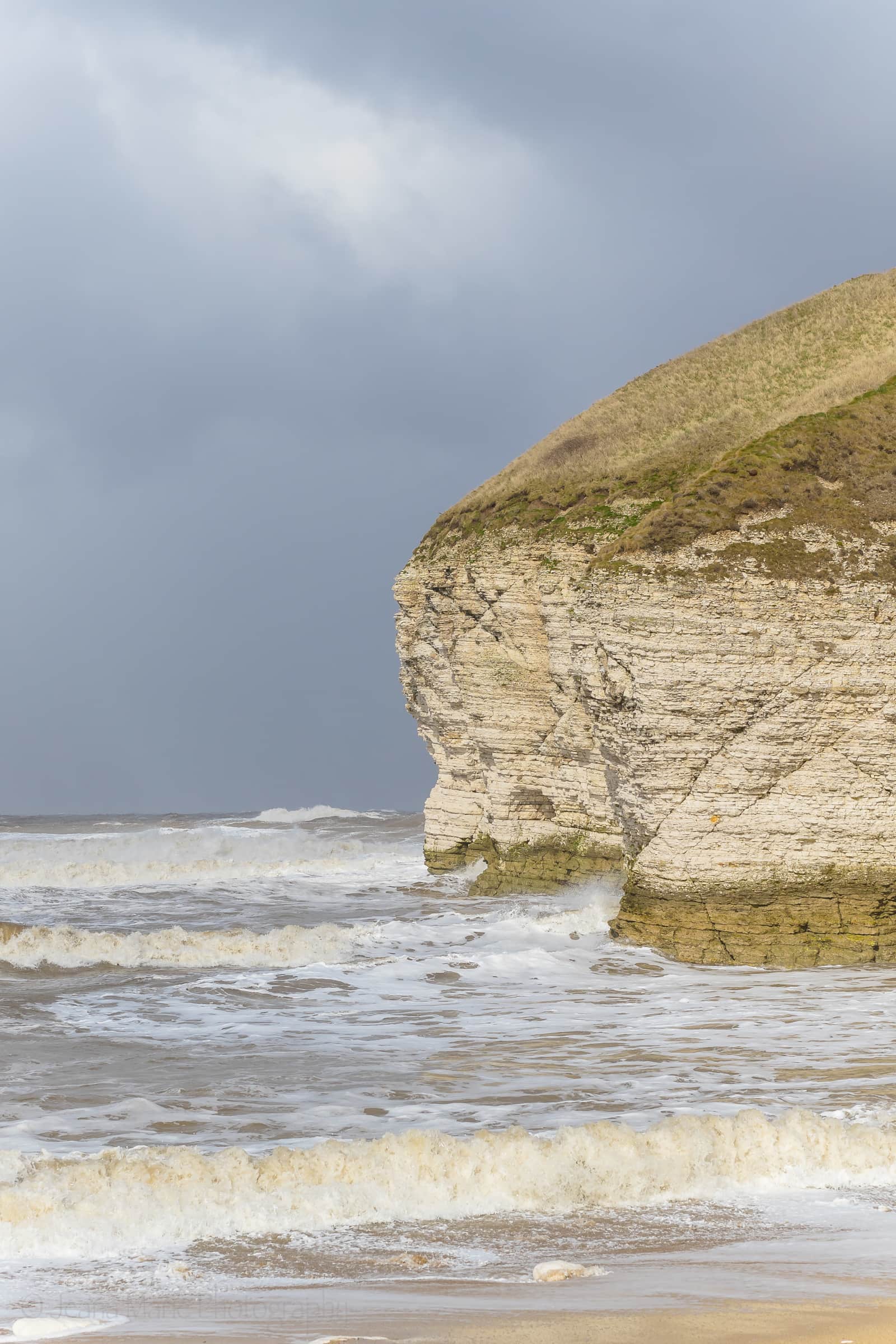 Pale chalk headland above choppy water beneath a grey sky