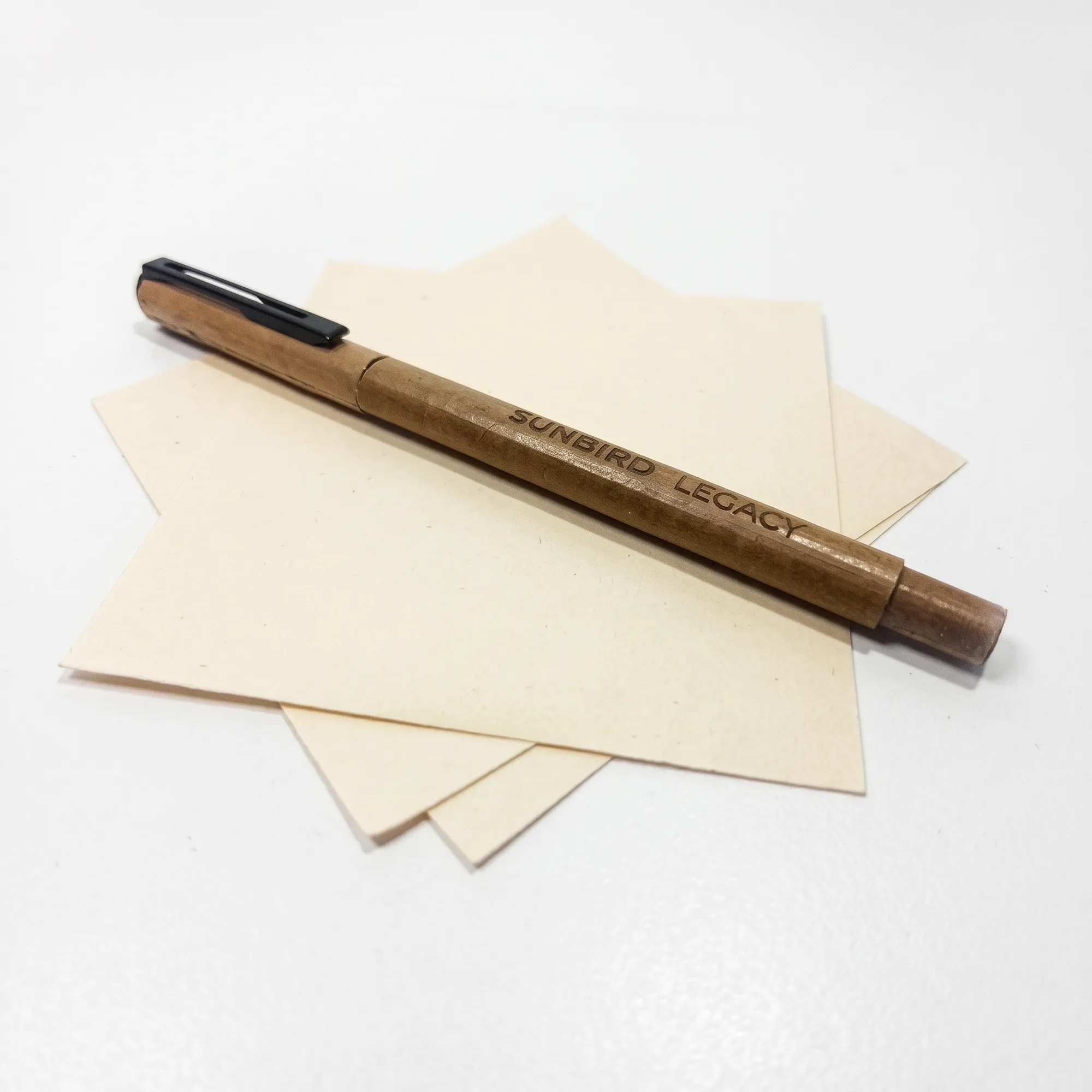 Dried Coconut Leaf Pen 15g pen resting on sheets of handmade paper — made in Sri Lanka, from Agromel UK