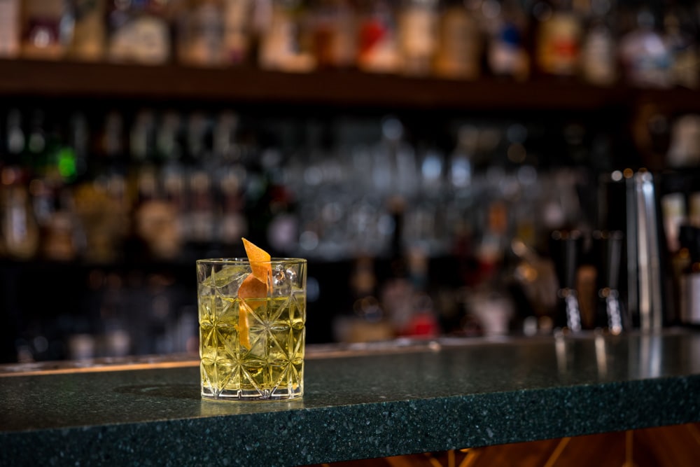 White mezcal negroni cocktail beautifully displayed on bar at best Amsterdam cocktail bar- Flying Dutchmen Cocktails. Image for Table Sage