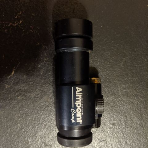 Aimpoint Comp from the early 90's. It works, but it's not exactly daylight bright anymore. Idk if it's the spring in the cap losing tension, or what, but... Its still old school AF, and plenty bright for an overcast day... And dark colored targets...