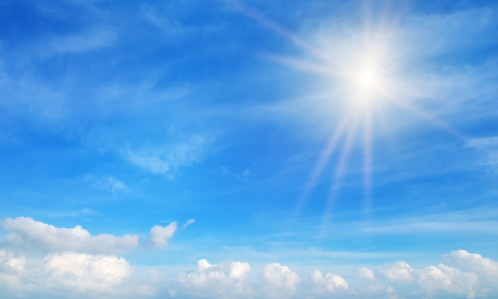 Blauer Himmel mit ein paar Wolken und der Sonne