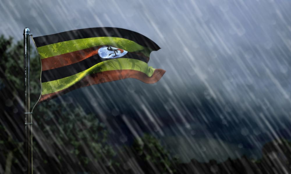 Die Fahne von Uganda ist im stürmischen Regenwetter zusehen 