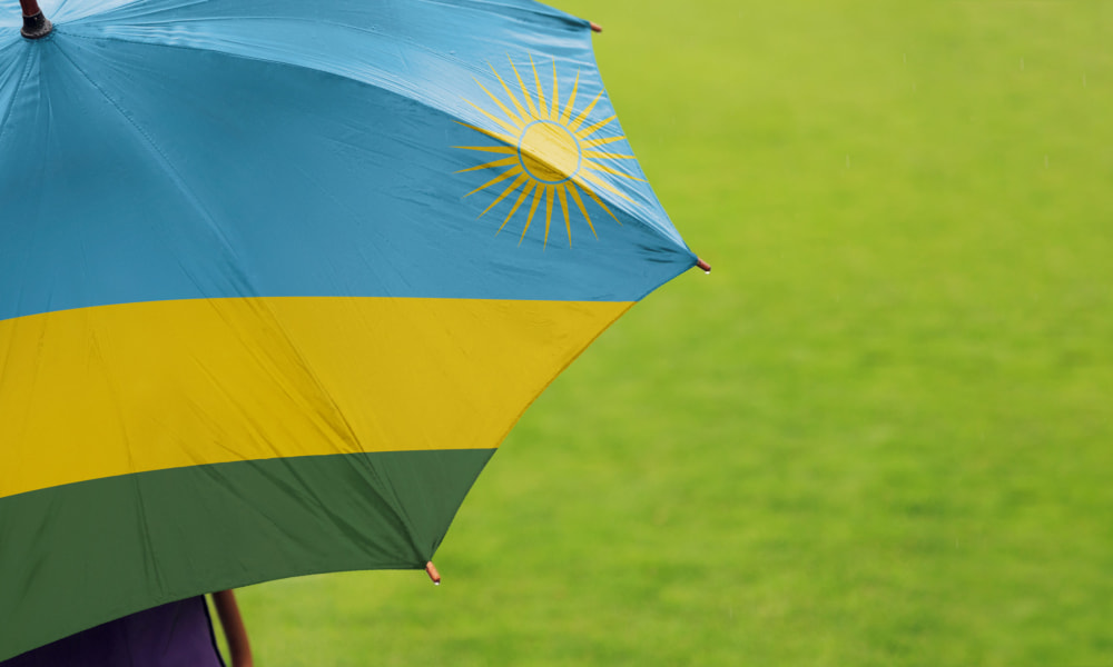 Gruene Wiese und ein Regenschirm mit der Ruanda Flagge
