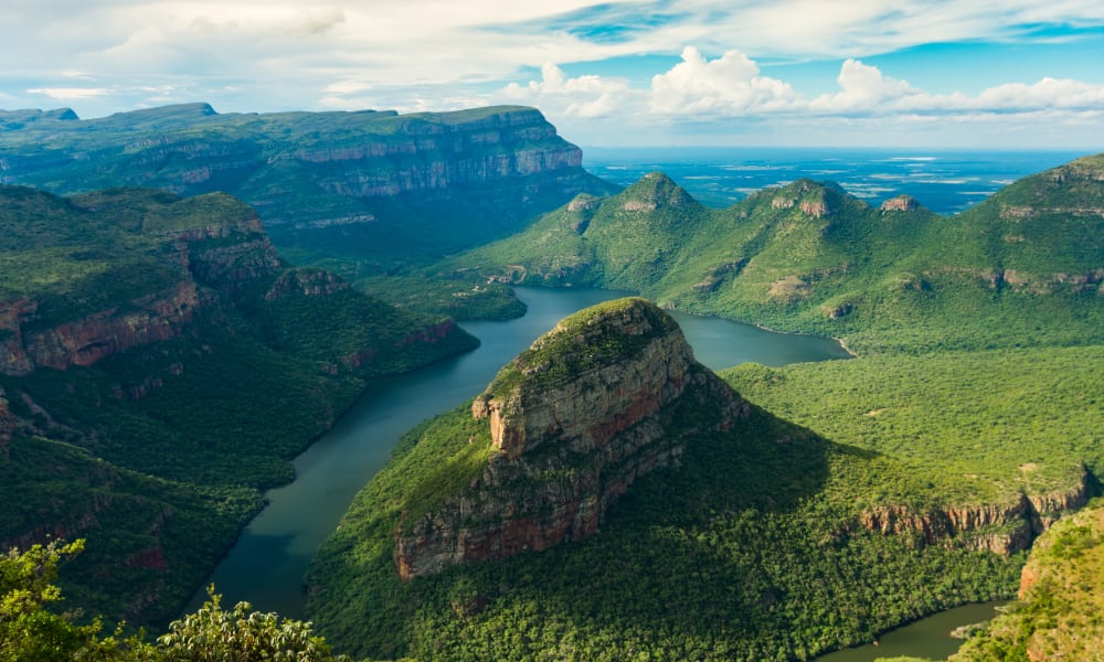 Eine spektakuläre Aussicht auf den Blyde River Canyon. Der Fluss windet sich durch die tiefen, grünen Täler, umgeben von majestätischen Felsformationen und üppigen Wäldern.