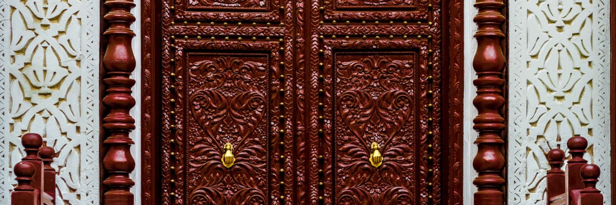 A big old wooden door with 2 gold handles and engravings