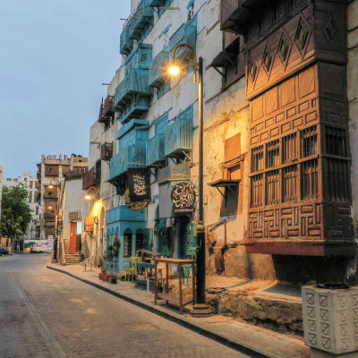 A view of an old street with 4 story buildings and street lamps in front