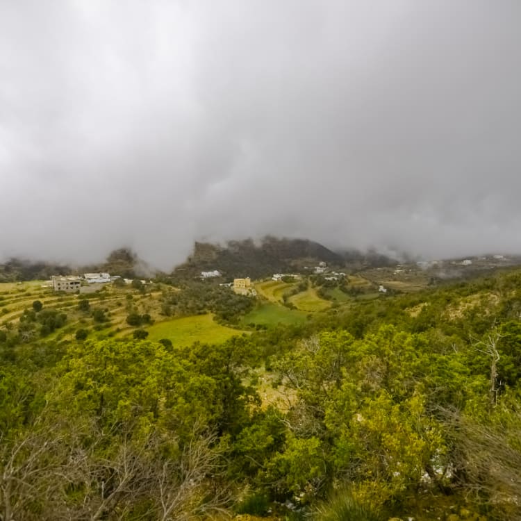 Die Sonne geht über der weiten und schönen Landschaft des Asir-Gebirges auf, mit einem von der Sonne beschienenen Felsgipfel im Vordergrund