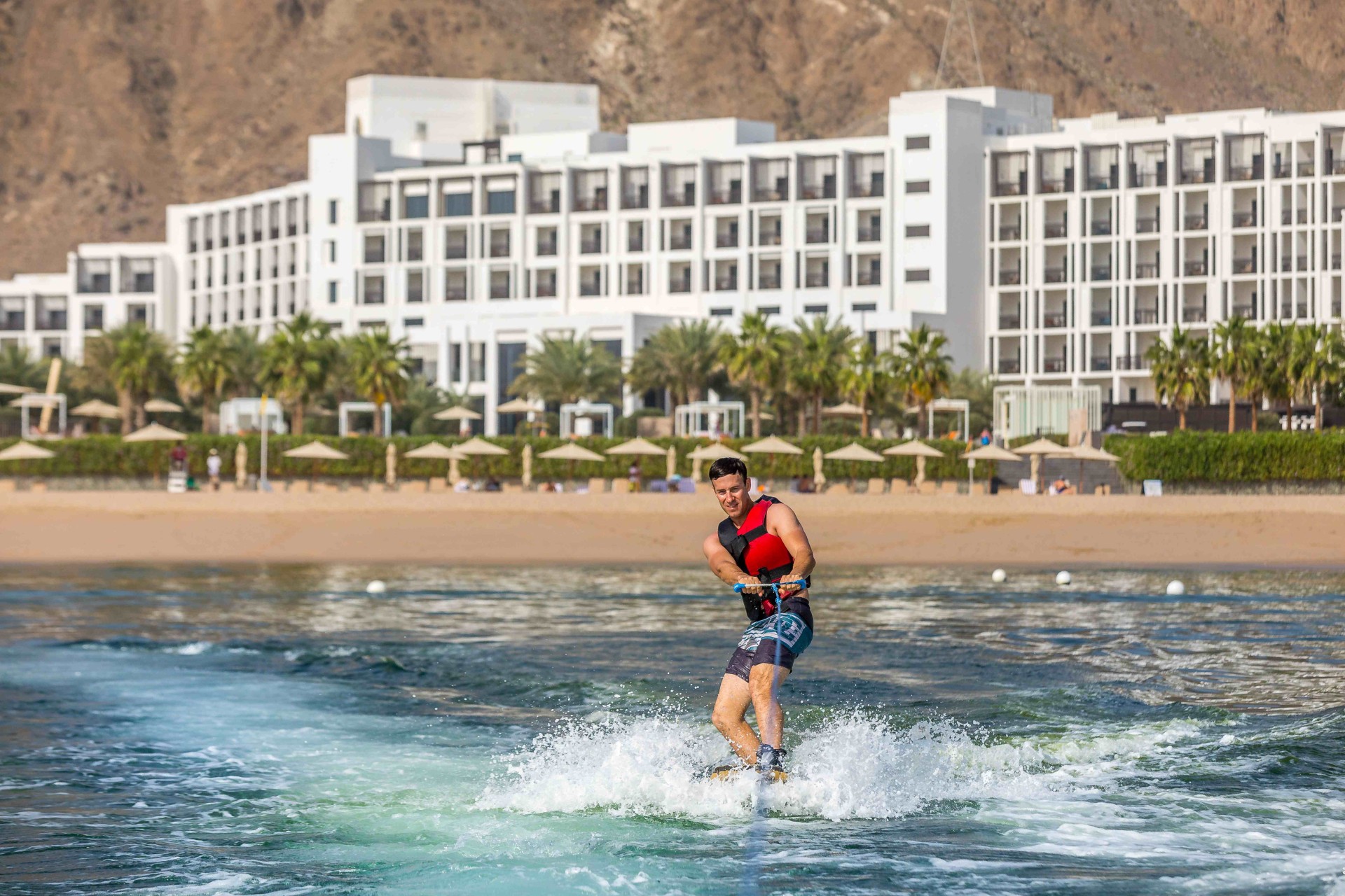 Wakeboarder und Hotelanlage im Hintergrund