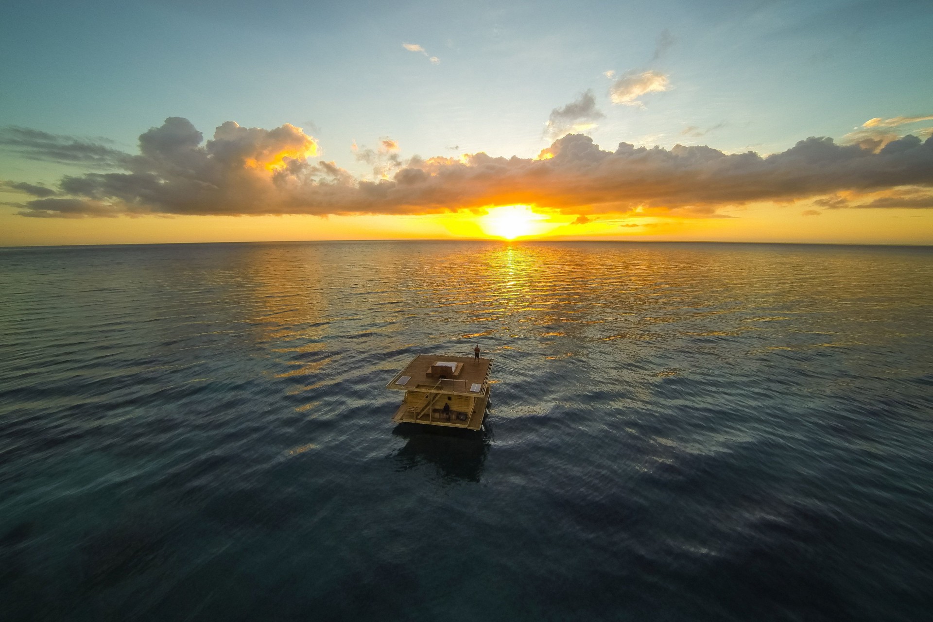 Blick auf ein Wasserbungalow bei Sonnenuntergang