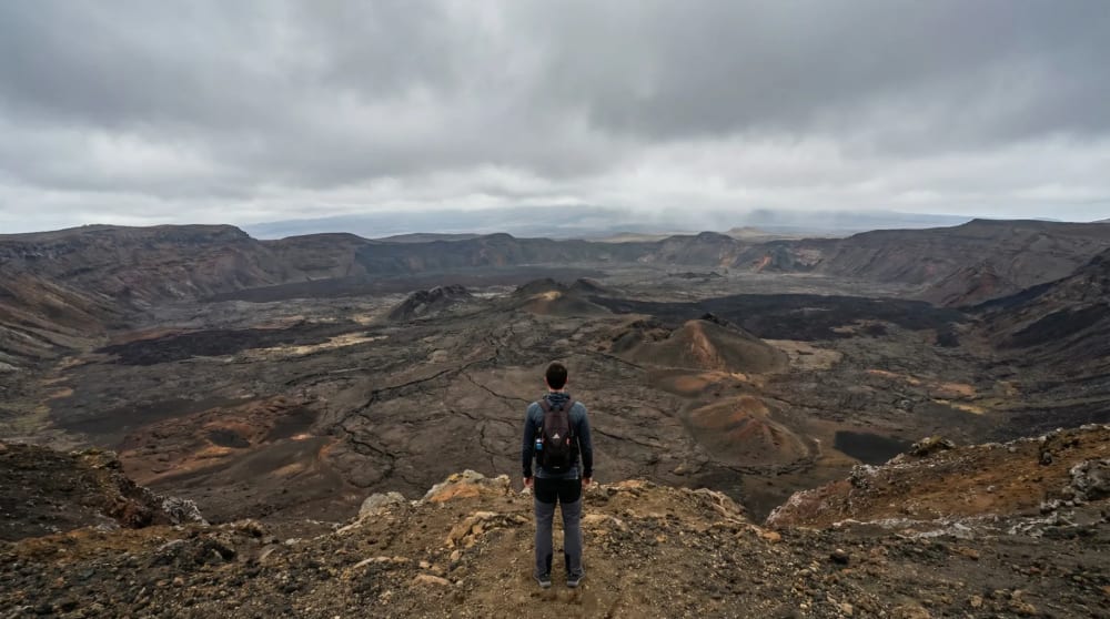 Wanderer am Rand des Sierra Negra Kraters auf Isabela mit Blick in die 10 km breite Caldera, Galapagos-Inseln