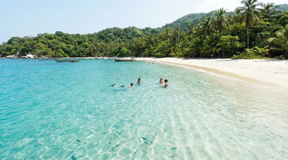Kristallklares tuerkisblaues Wasser an Playa Cristal im Tayrona-Nationalpark mit Schnorchlern ueber bunten Korallen — Schnorcheln Kolumbien Karibik