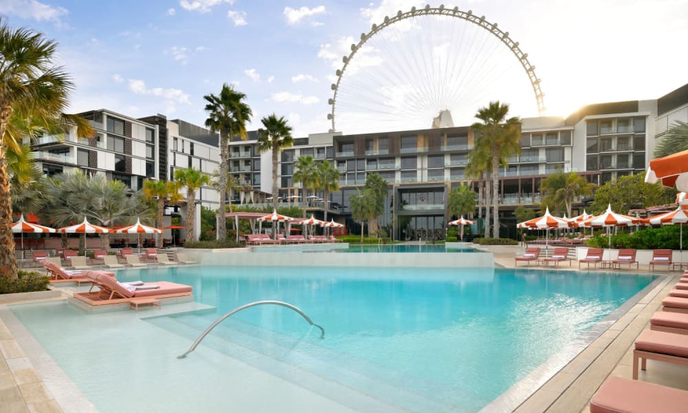Luxus-Hotelpoolbereich im Banyan Tree Dubai mit Riesenrad im Hintergrund bei teilweise bewölktem Himmel.