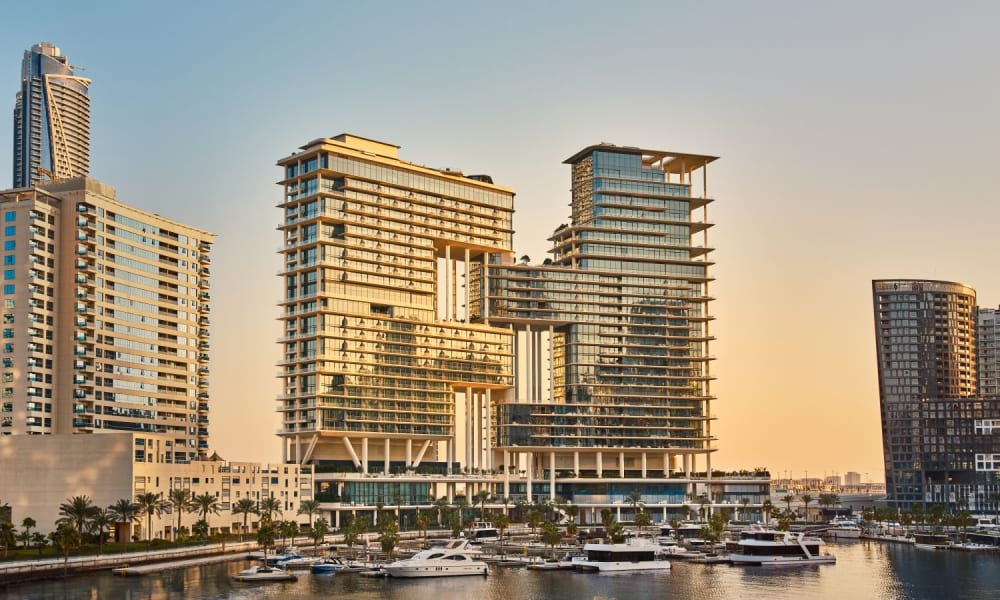 Modern high-rise buildings near a marina during sunset.