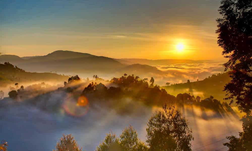 Sonneuntergang ueber den wolkenverhangenen Bergen Ugandas
