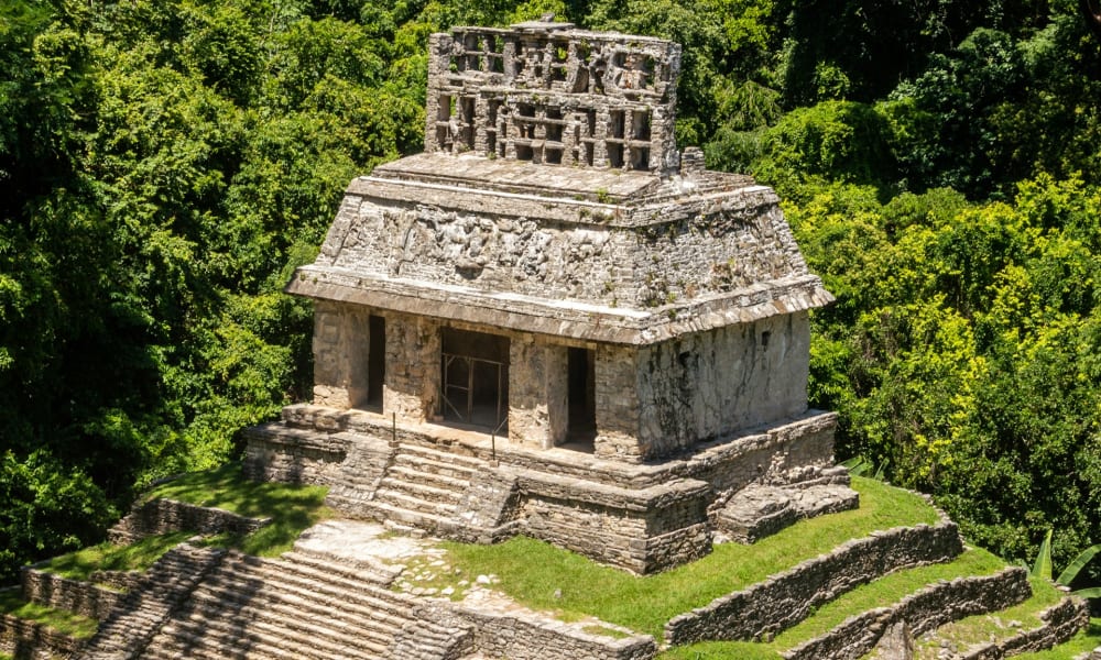 Antike Stein-Tempelruinen umgeben von dichtem grünem Dschungel in Palenque, Chiapas, Mexiko.