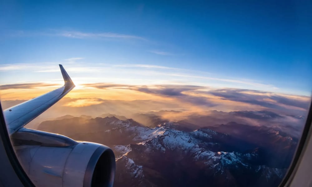 Flug nach Kolumbien - Blick aus dem Flugzeugfenster auf die schneebedeckten Gipfel der kolumbianischen Anden bei Sonnenaufgang