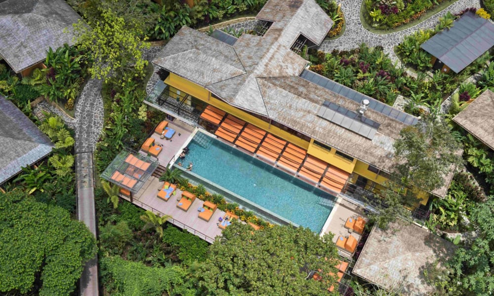 Aerial view of Nayara Springs resort showing the main building, swimming pool, and surrounding lush greenery in Costa Rica.