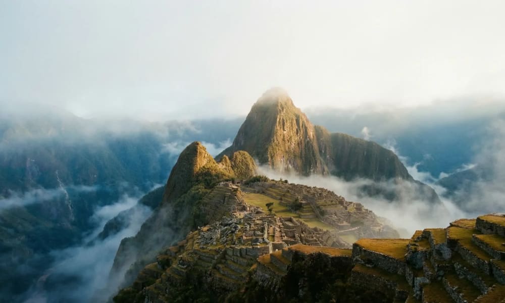 Machu Picchu im Morgengrauen — Inka-Ruinen im Nebel mit Huayna Picchu im warmen Sonnenlicht