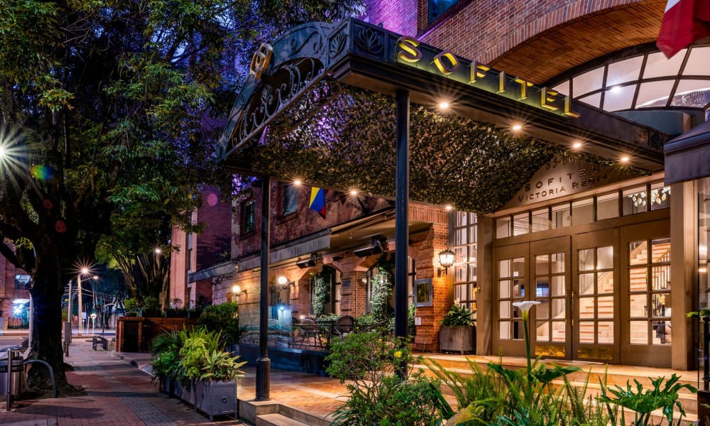 Der Eingang des Sofitel-Hotels in Bogotá, dekoriert mit Pflanzen und warmem Licht am Abend.