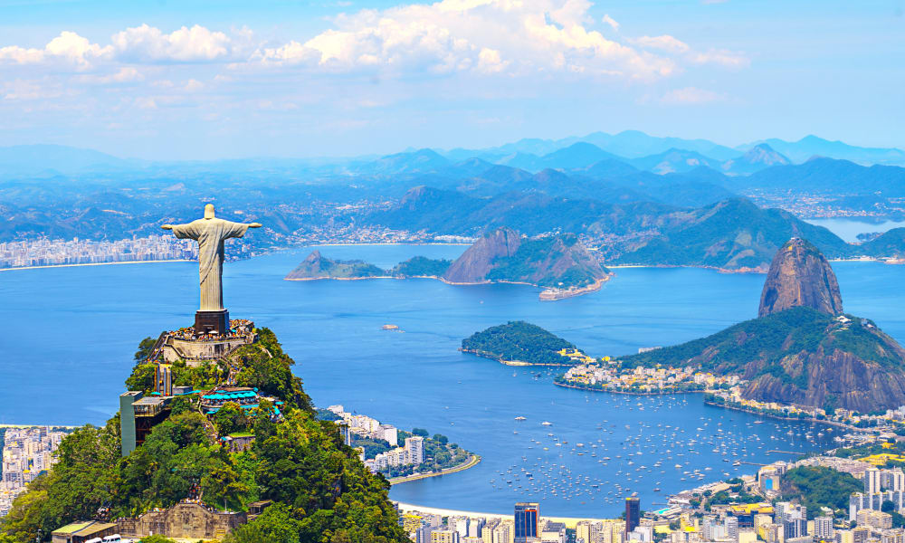 A panoramic view of Rio de Janeiro featuring the Christ the Redeemer statue on Corcovado Mountain overlooking the city and bay.