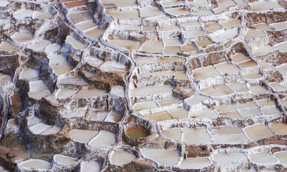 Terrassierte Salztümpel an einem Hang in Maras, Cusco, Peru, mit verschiedenen Stadien der Salzkrustenbildung.