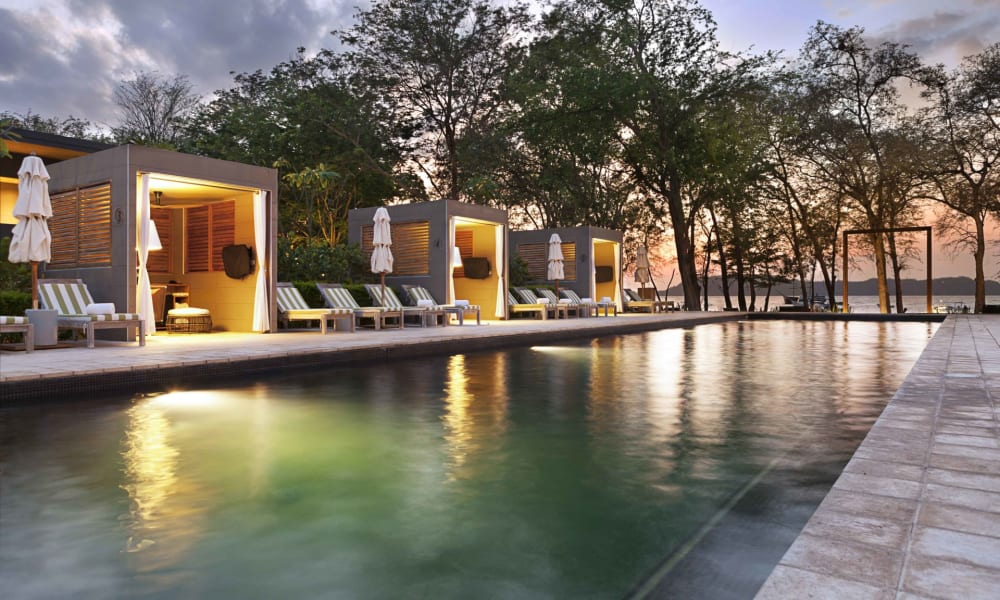 Luxusanlage im Freien mit Pool, Cabanas und Liegestühlen bei Sonnenuntergang in Costa Rica