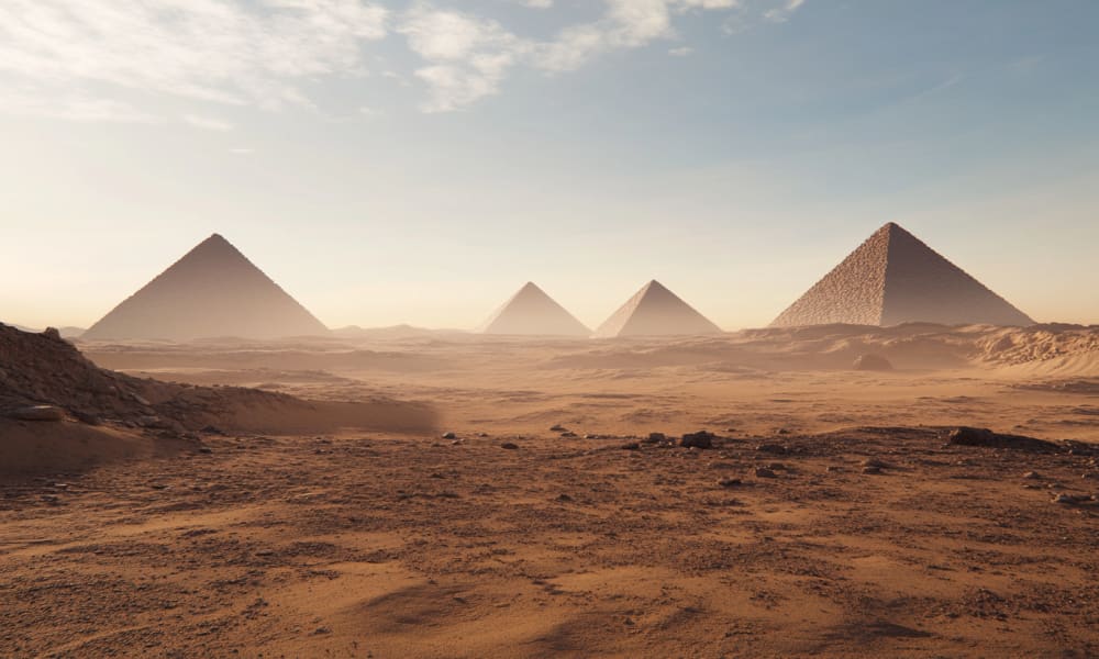 Ancient Egyptian pyramids rising over a desert landscape at sunset.