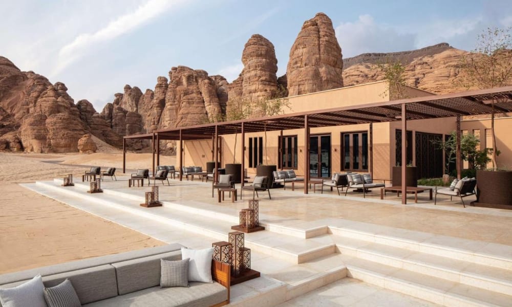 Luxurious outdoor lounge area with modern furniture and a shaded patio, set against a backdrop of distinctive sandstone rock formations.