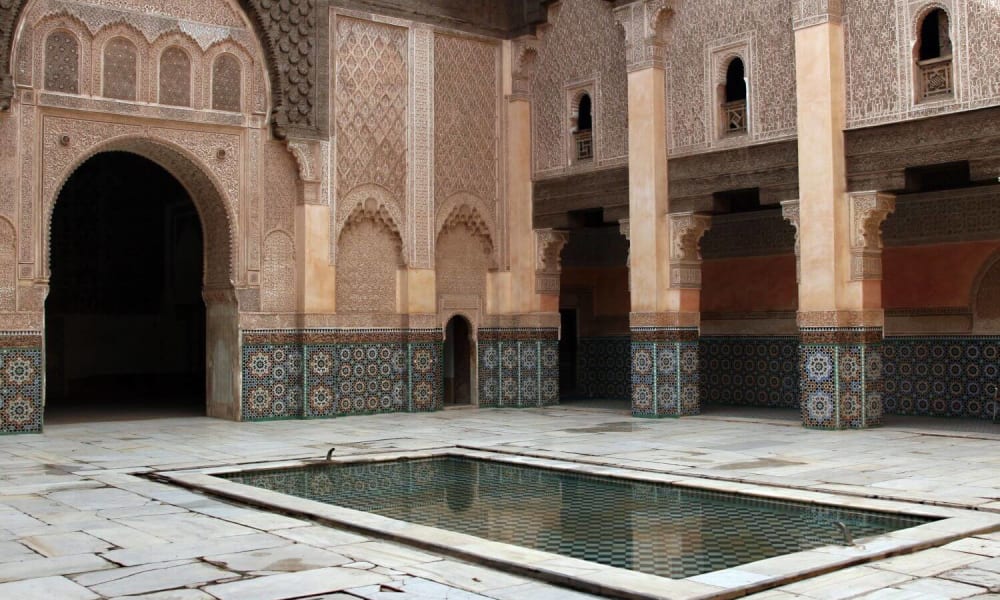 An inner courtyard of a traditional Moroccan building with intricate architectural details and a central fountain.