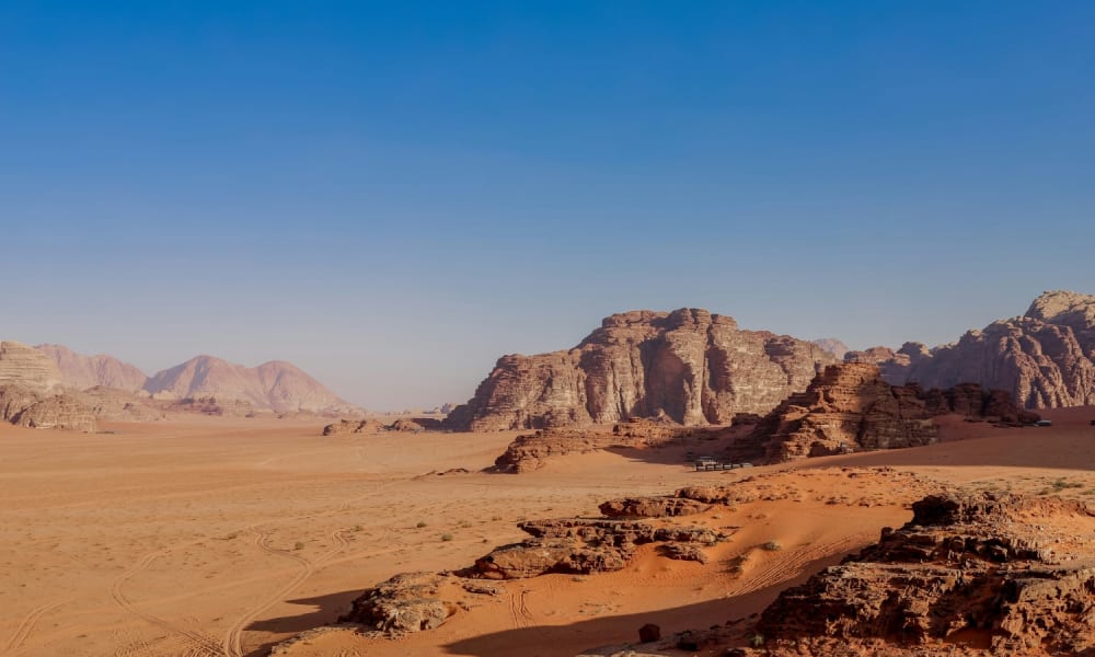 Expansive desert landscape in Wadi Rum with rocky formations under a clear blue sky.