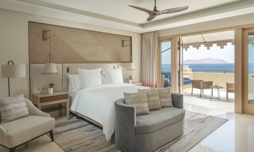 Luxus-Suite mit großem Bett, Sitzecke und Balkon mit Blick auf das Meer in einem Four Seasons Resort.