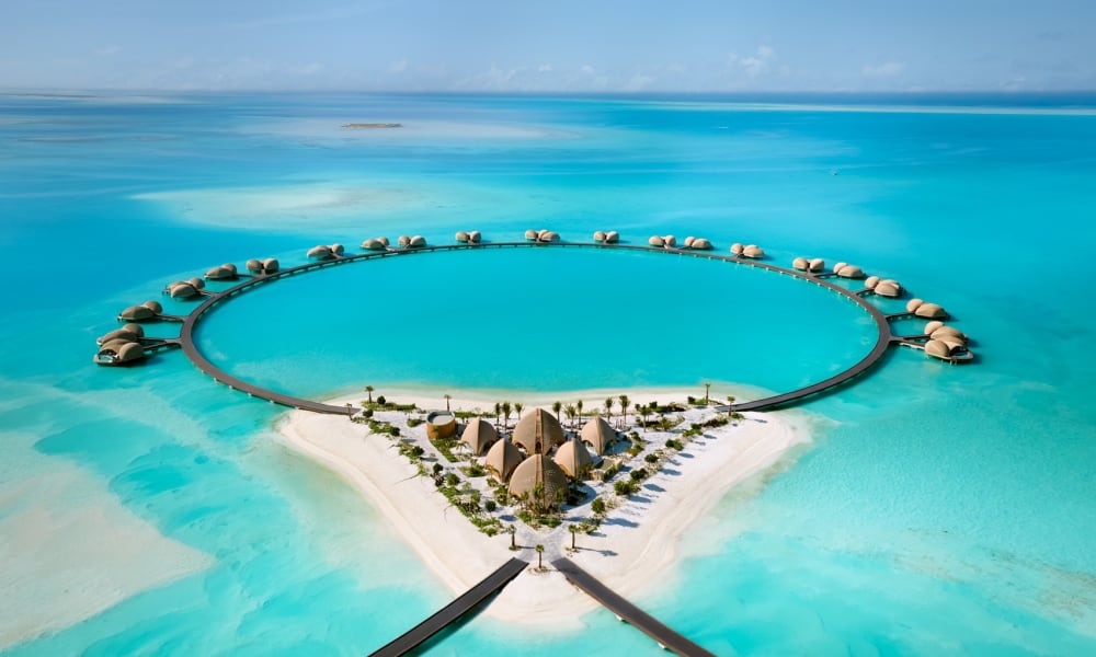Luxushotel mit Wasserbungalows und einem großen kreisförmigen Pool am Strand am Roten Meer.