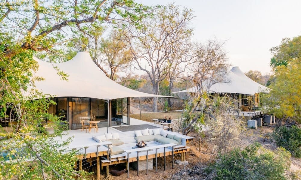A luxurious tented camp with a spacious outdoor terrace surrounded by trees in South Africa.