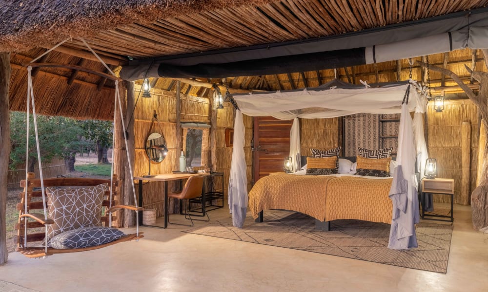 Inside a rustic safari room with a canopy bed, sitting area with a swing, and warm lighting