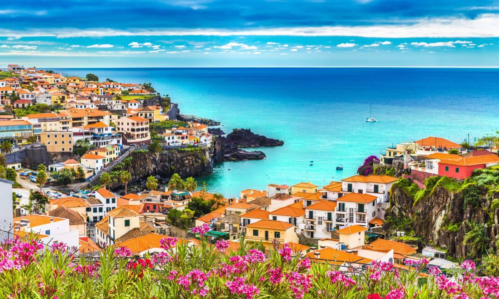 Lebendige Küstenstadt auf Madeira mit bunten Häusern auf Klippen mit Blick auf den Atlantik.