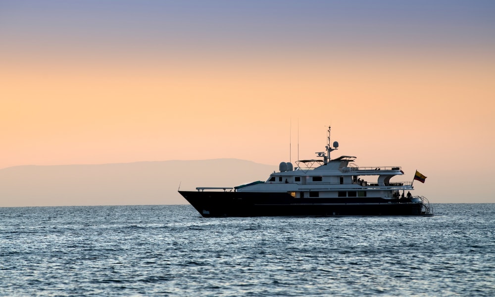 Luxusyacht, die bei Sonnenuntergang auf dem ruhigen Ozean vor den Galápagos-Inseln fährt.
