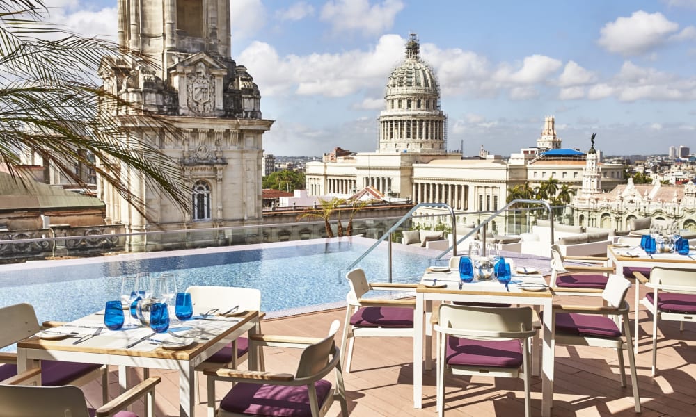 Dachterrasse mit Tischen und Stühlen, die auf die Stadt Havana in Kuba blicken, mit dem Kapitol im Hintergrund.