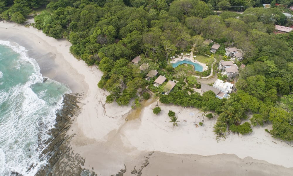 Aerial view of Nantipa Beach Resort with a sandy beach, lush green forest, swimming pool, and beachfront bungalows in Costa Rica.