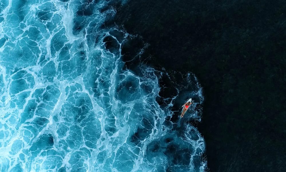 A surfer riding a wave close to the dark ocean in Nihi Sumba.