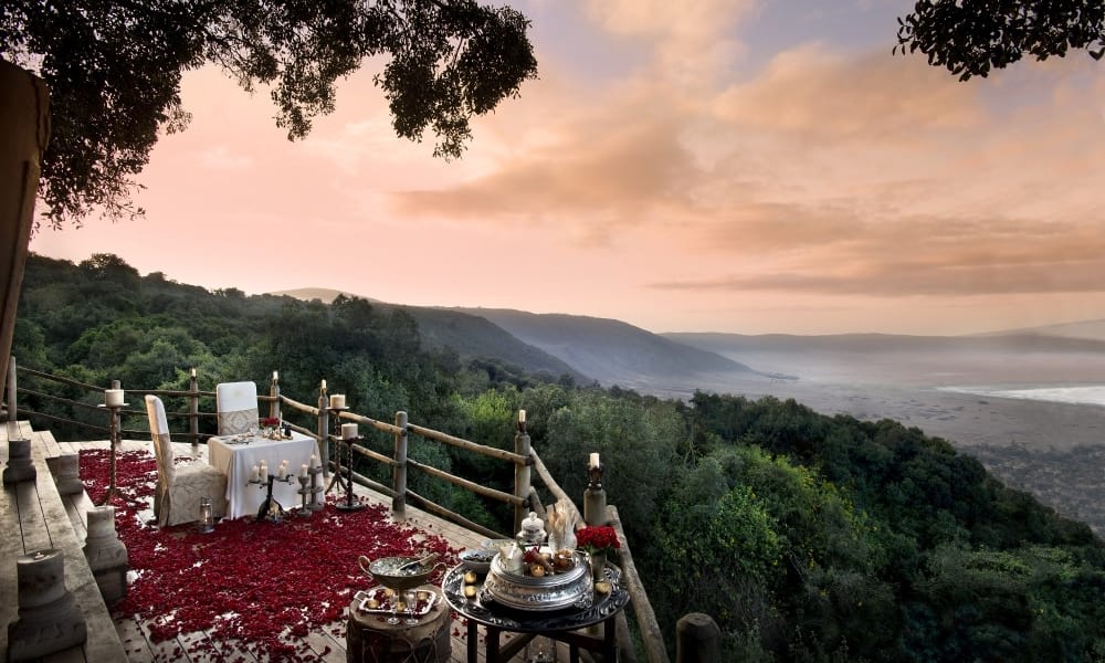 Ein luxuriöses privates Abendessen auf einem Hügel mit Blick auf üppiges Grün und eine entfernte Talansicht bei Sonnenuntergang.