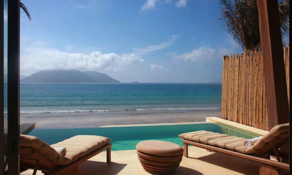 Blick von einer Luxusvilla mit Blick auf den Strand und das Meer, mit Liegen im Freien und einem Pool.
