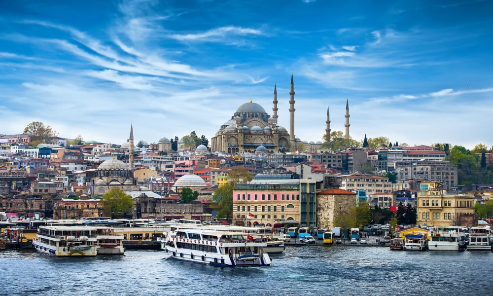 A panoramic view of Istanbul with a large mosque and boats on the Bosphorus.