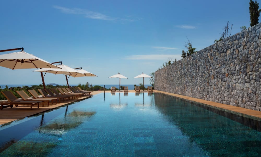 Luxury outdoor pool area with lounge chairs and umbrellas overlooking a scenic landscape in Turkey.