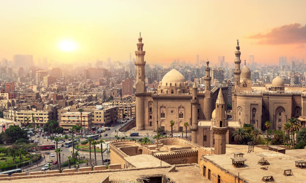Sonnenuntergang über Kairo mit historischen Moscheen und modernen Gebäuden.