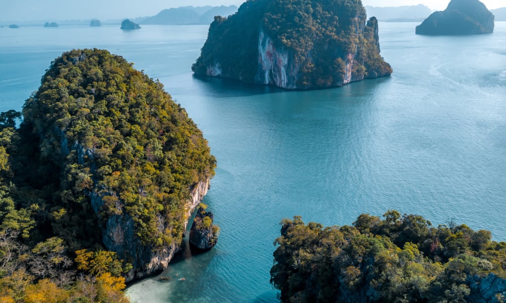 Limestone islands and lush greenery in Phang Nga Bay viewed from above.