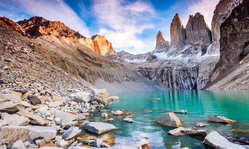 Ein ruhiger türkisfarbener See, umgeben von zerklüfteten Berggipfeln und felsigen Ufern in Patagonien.