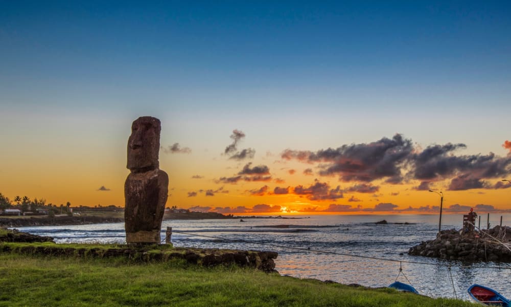 Moai statue on Easter Island with a sunset over the ocean in Hanga Roa.