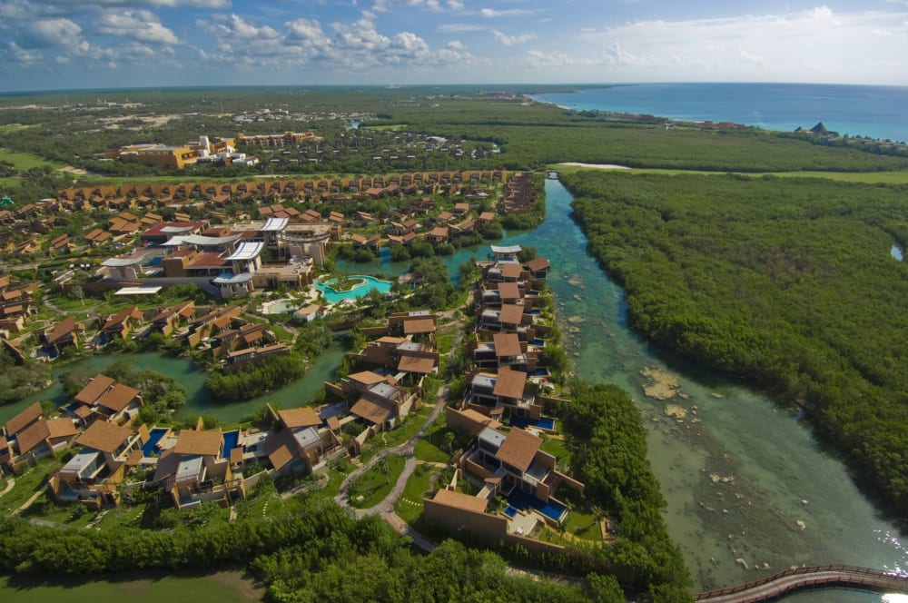 Luftaufnahme des Banyan Tree Mayakoba Resorts mit Villen, umgeben von grünen Mangroven und klaren Wasserwegen nahe der Küste.