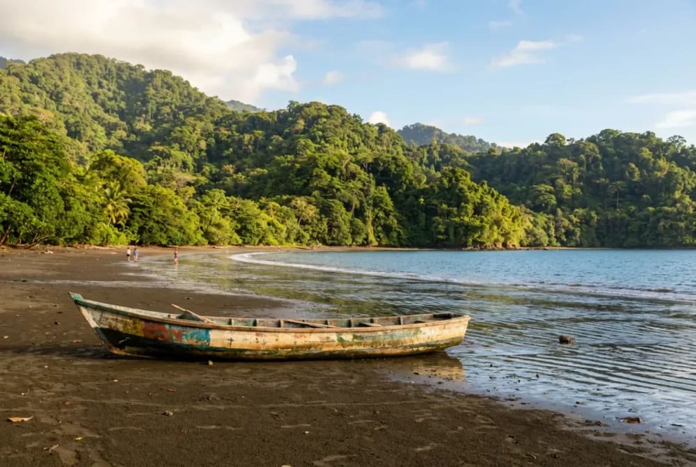 Drake-Bay-Bucht auf der Osa-Halbinsel Costa Rica mit Holzboot am Strand und Regenwald im Hintergrund