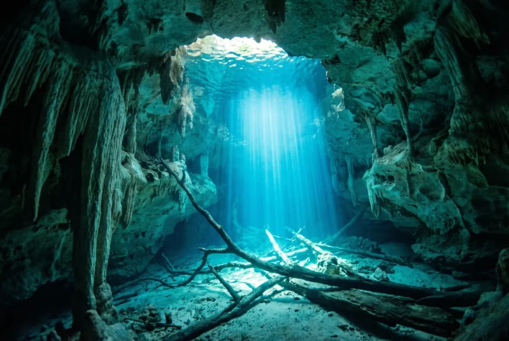 Sonnenstrahl im kristallklaren türkisblauen Wasser der Unterwasserhöhle Poço Azul in der Chapada Diamantina